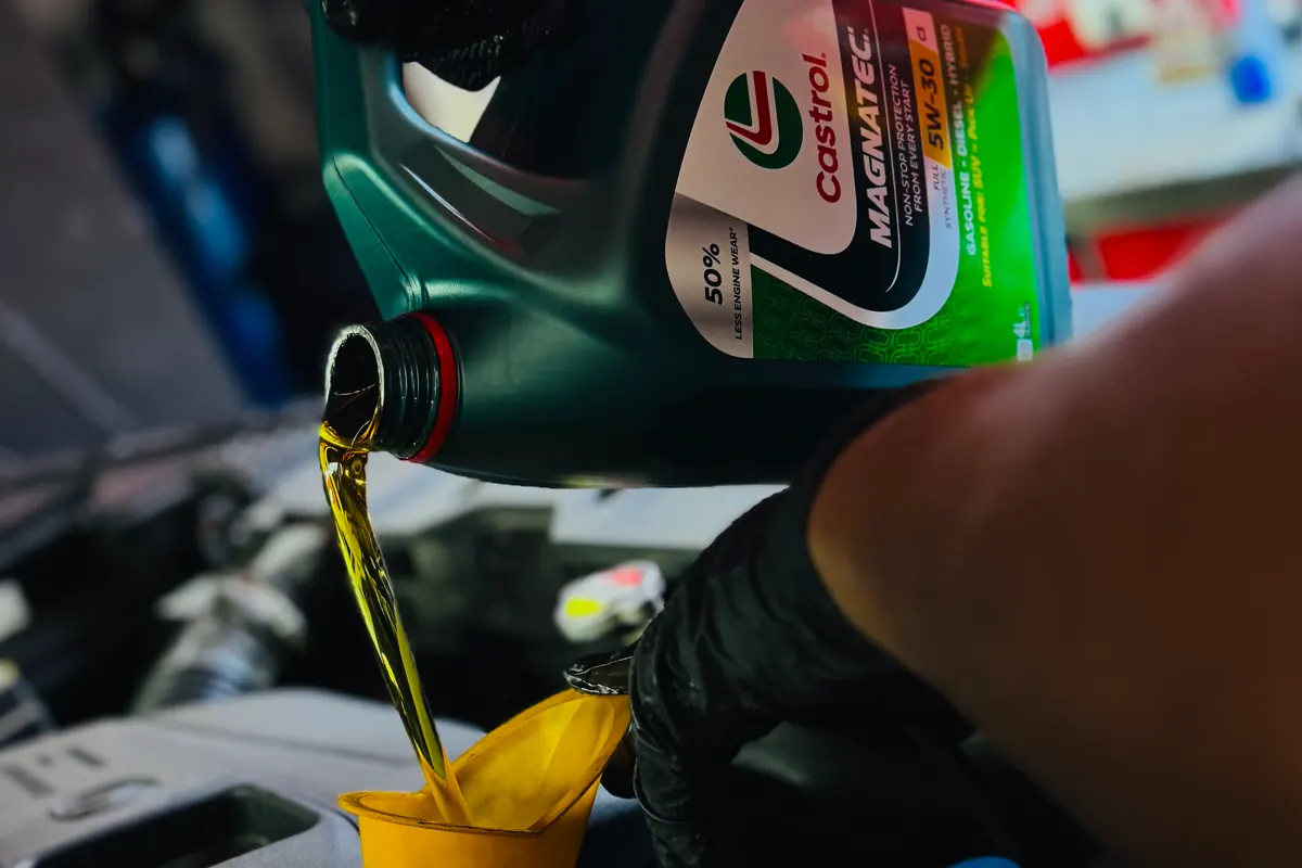 Técnico vertiendo aceite en el motor con un embudo